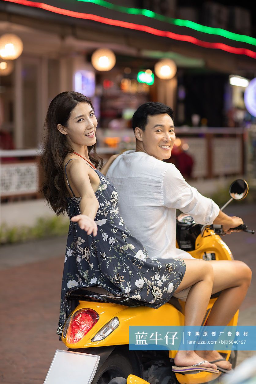 快乐的年轻情侣骑摩托逛夜市