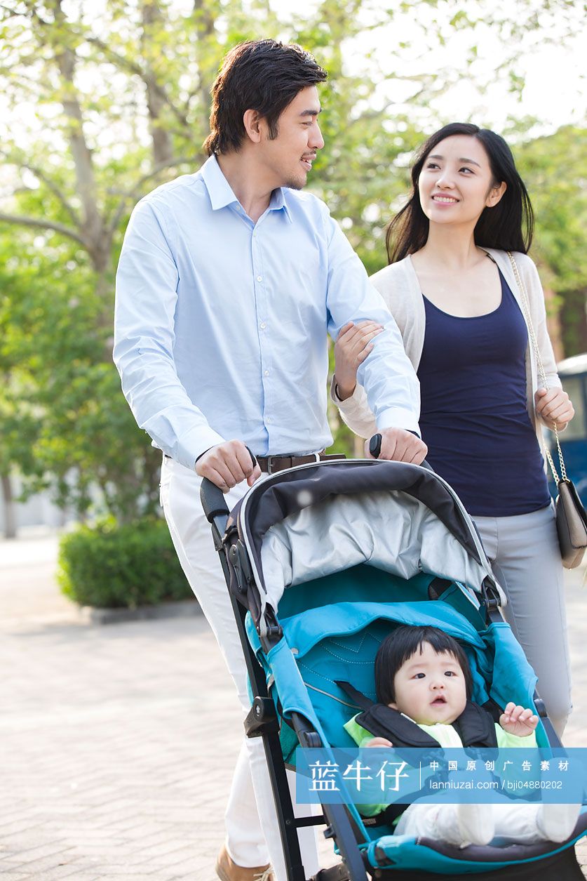 年轻夫妻推着婴儿车散步