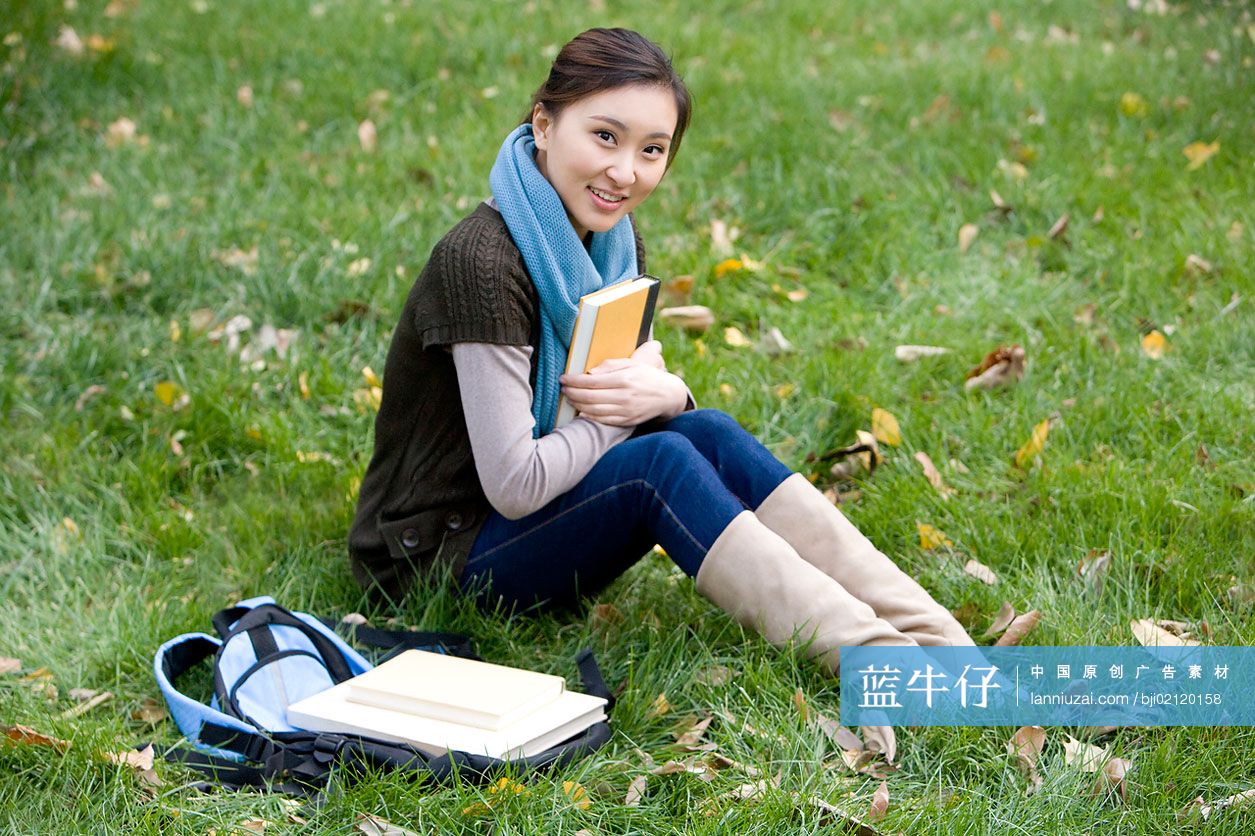 青年女子坐在草地上看书