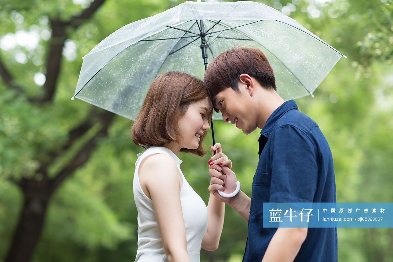 年轻情侣打着雨伞