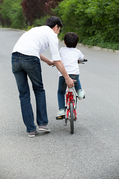 年轻父母教女儿骑自行车
