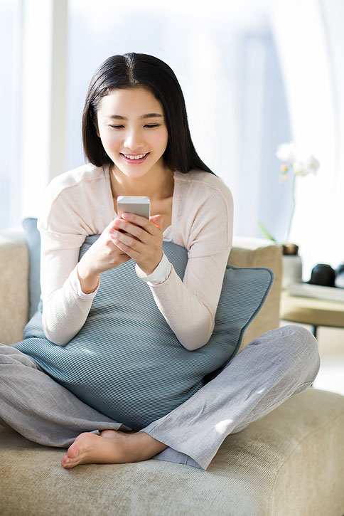 年轻女子坐在沙发上玩手机