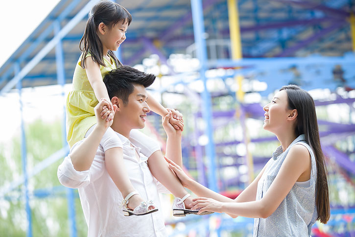 快乐的年轻家庭在游乐园嬉戏