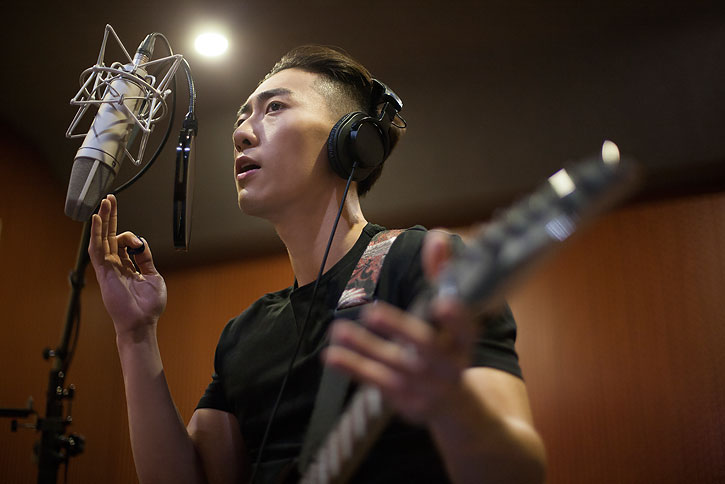 年轻男子在录音棚唱歌弹吉他