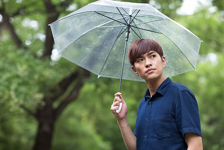 快乐的年轻男子打着雨伞