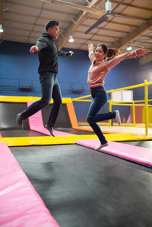 快乐的年轻情侣玩蹦蹦床-原创广告素材图片-蓝牛仔