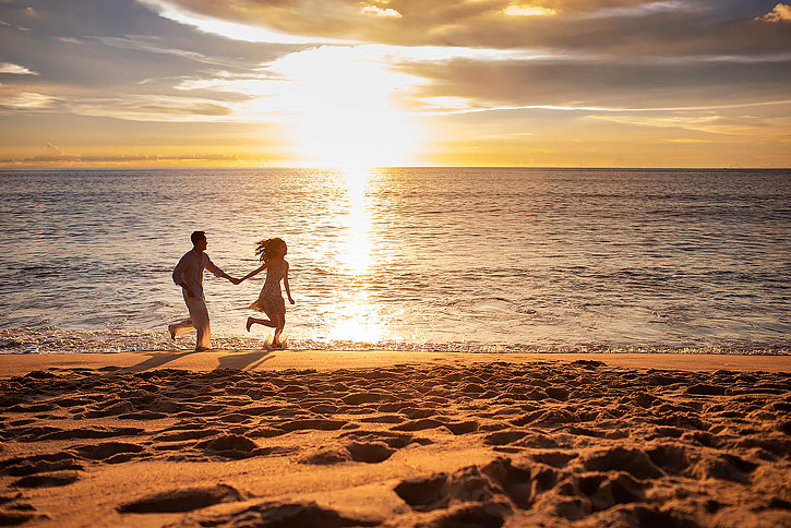 快乐的年轻夫妇在沙滩奔跑
