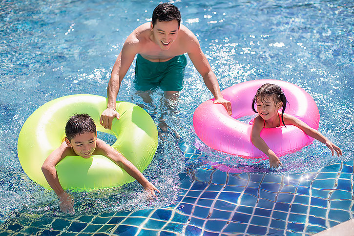 快乐的年轻家庭在泳池里玩耍