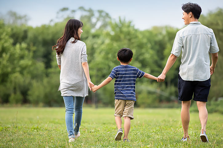 快乐年轻家庭在草地上散步