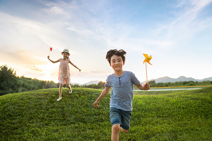 儿童拿着风车在草地上奔跑