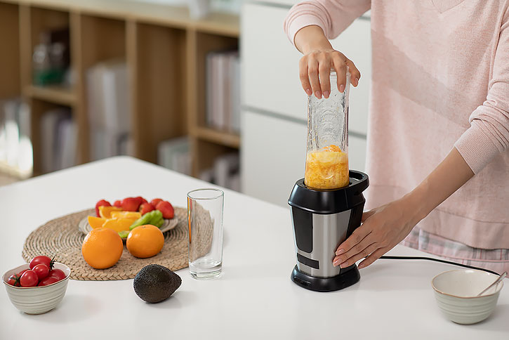 快乐年轻女士在家榨果汁