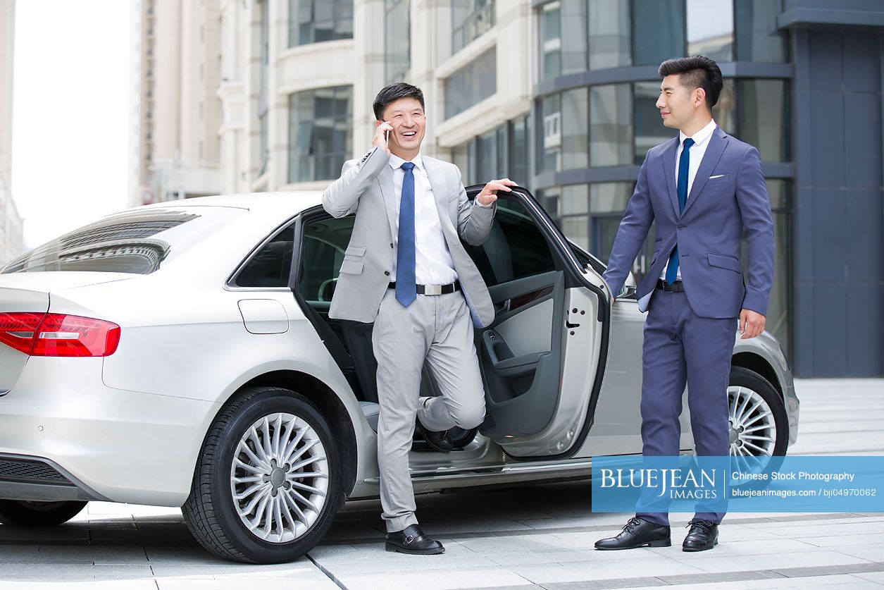 Confident Chinese businessman getting off car