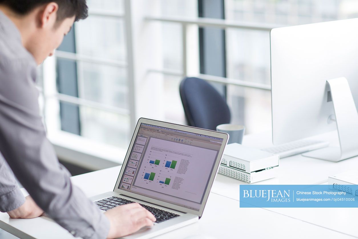 Young Chinese businessman using laptop in office