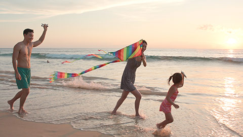 Happy young Chinese family flying a kite on beach,4K