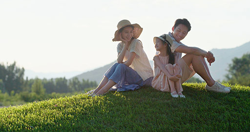快乐的年轻家庭坐在草地上