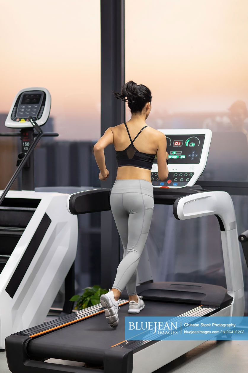 Young Chinese woman exercising on treadmill at gym