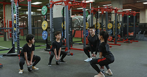 Active Chinese children having exercise class with their coach in gym,4K