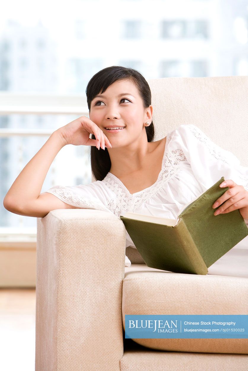 Chinese woman reading on a sofa