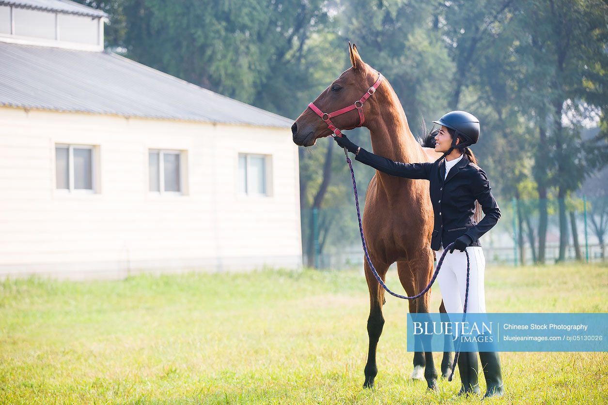 Cheerful Chinese female rider with her horse