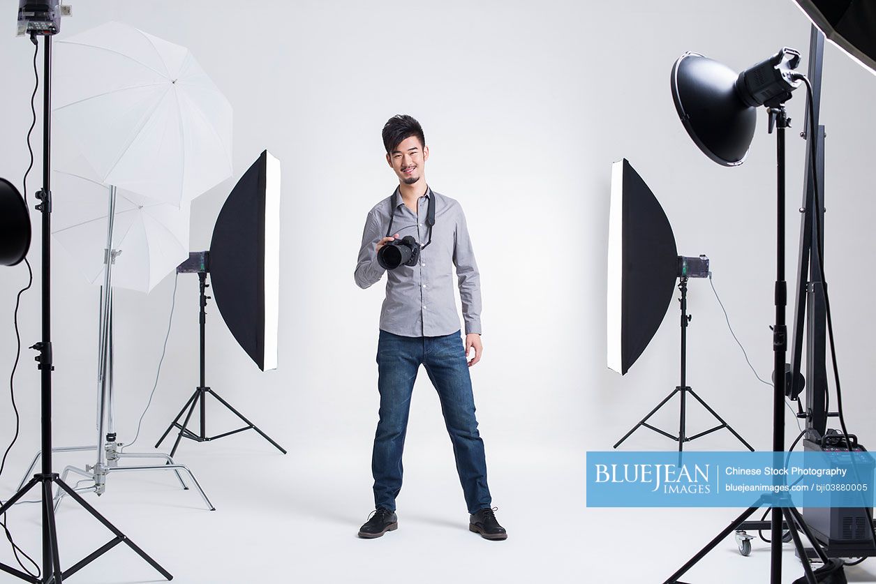 Chinese photographer standing in studio with camera
