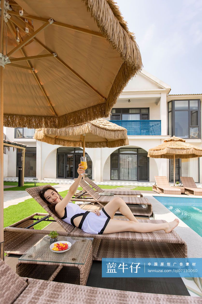 年轻女子在躺椅上喝果汁