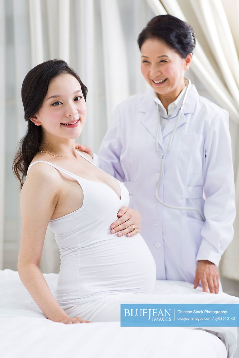 Portrait of happy pregnant Chinese woman and doctor