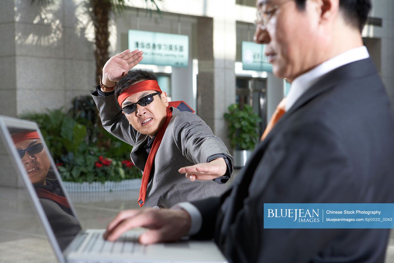 Chinese businessman in headband and sunglasses doing karate movesHighres stock photo for download