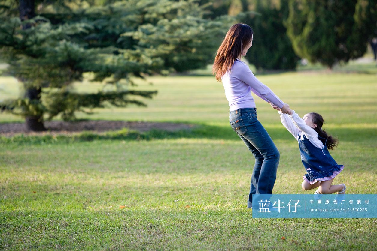 女儿被妈妈拉起来在草地上玩耍