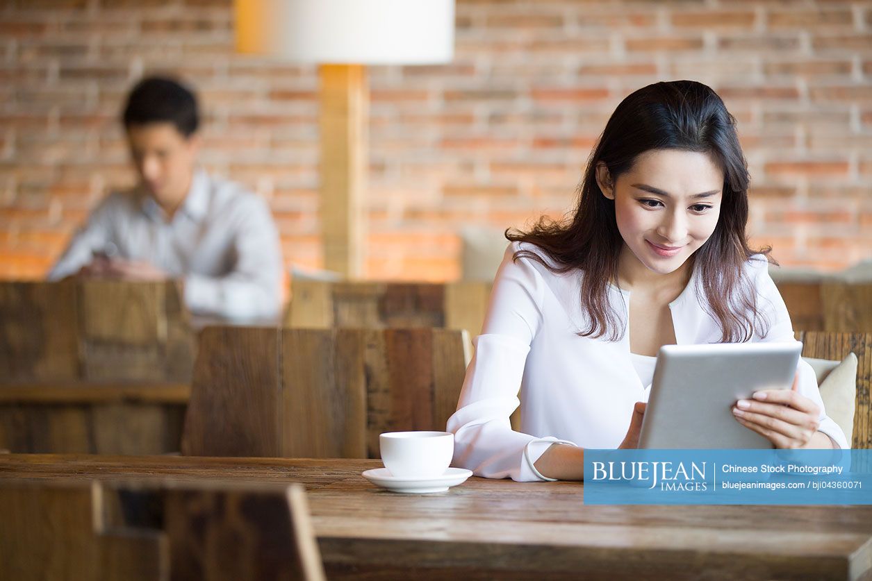 Young Chinese woman using digital tablet in cafe