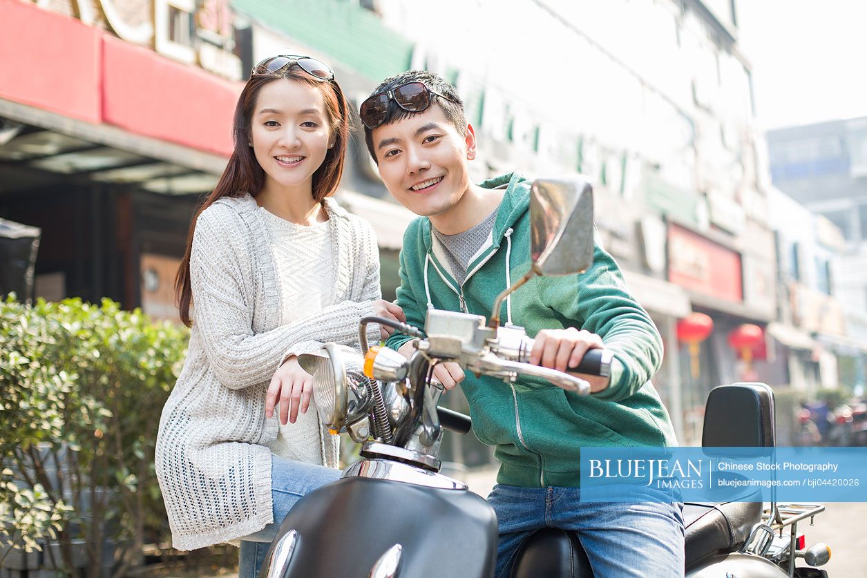 Young Chinese couple riding motorcycle together