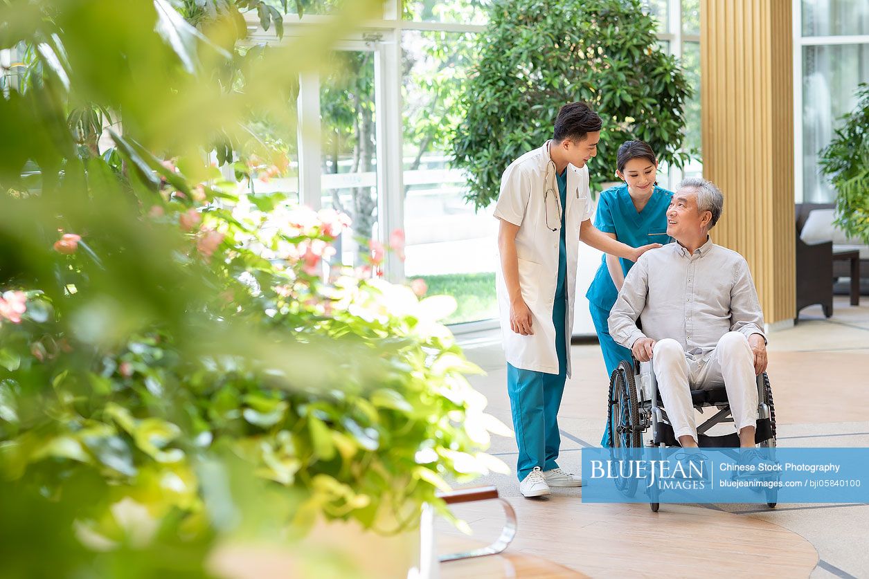 Young Chinese doctor talking with patient in nursing home