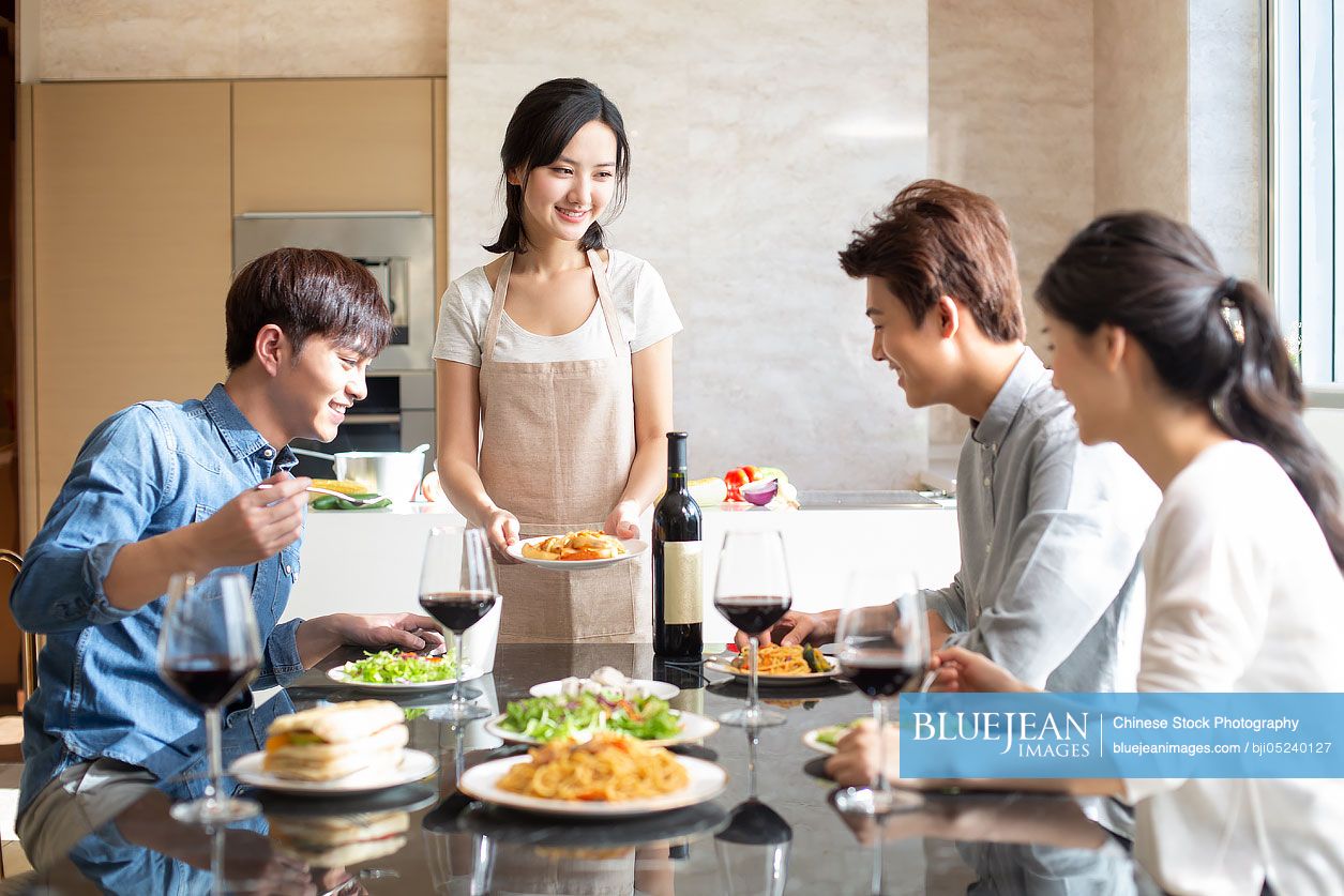 Young Chinese friends dining together at home