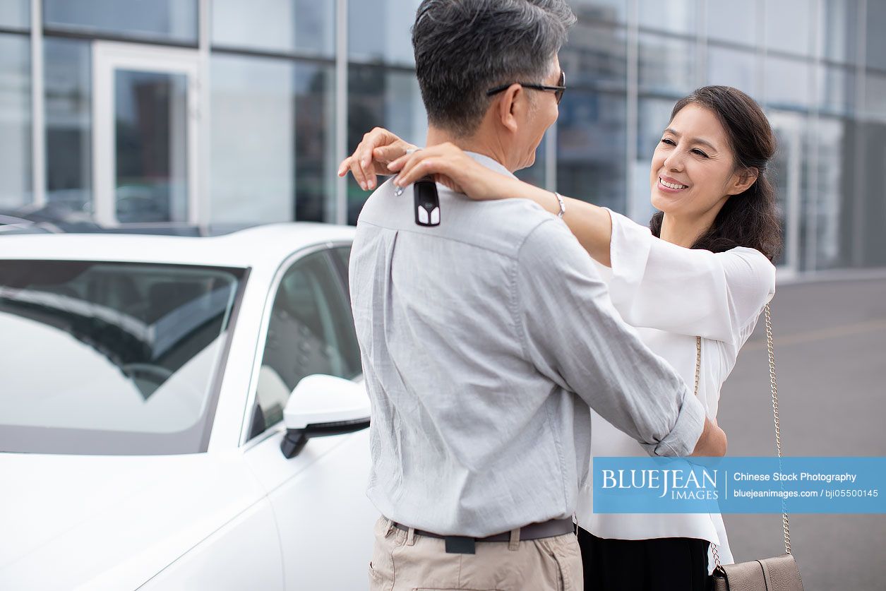 Happy mature Chinese couple buying car