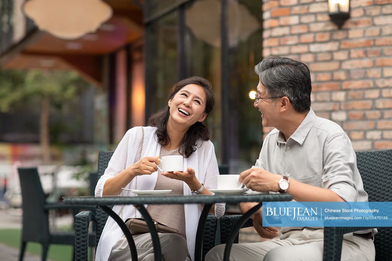 Mature Chinese couple drinking coffee in coffee shop