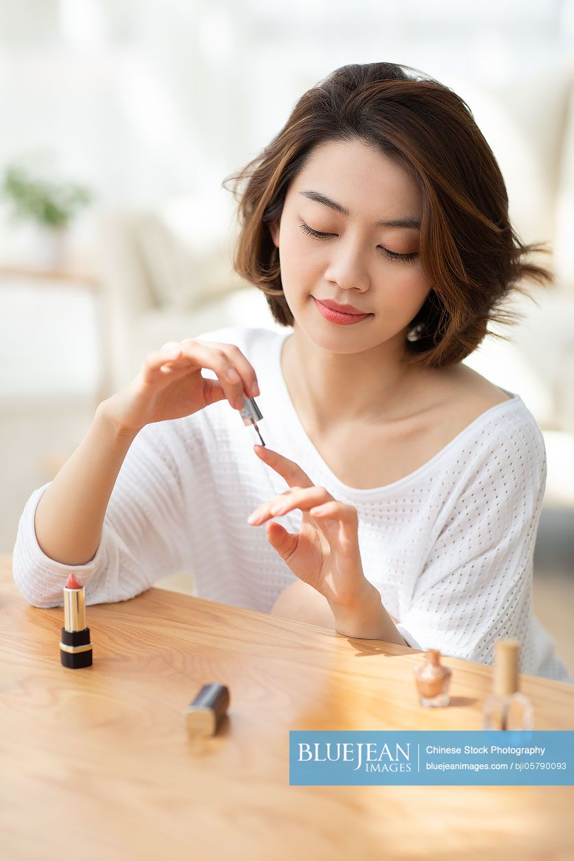 Young Chinese woman applying nail polish at home-High-res stock photo for  download