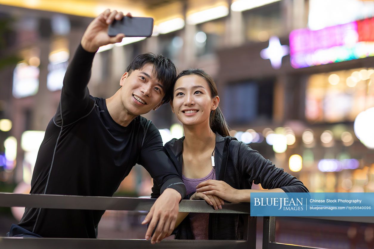 Young Chinese couple taking selfie after exercising