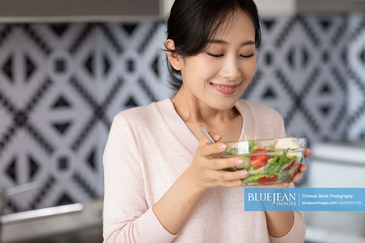 Young Chinese woman cooking in kitchen