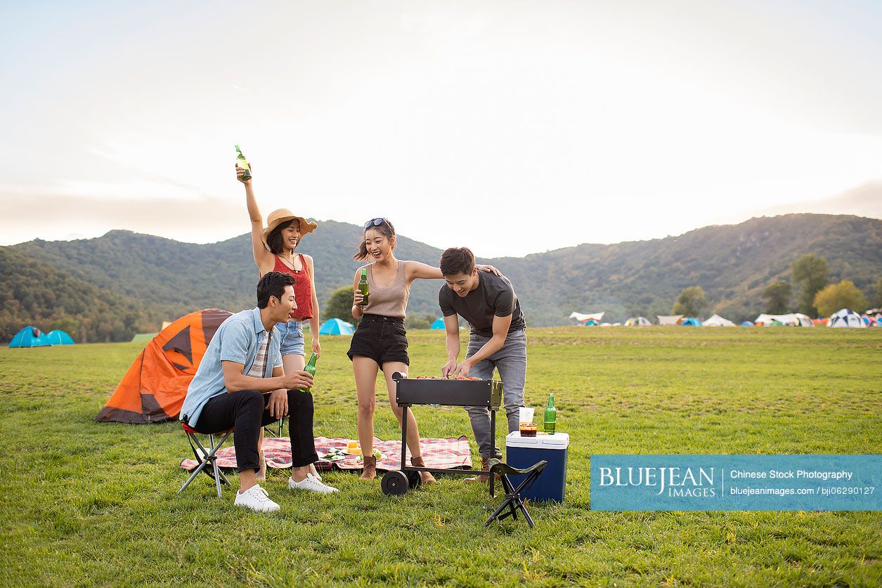 Happy young Chinese friends barbecuing outdoors