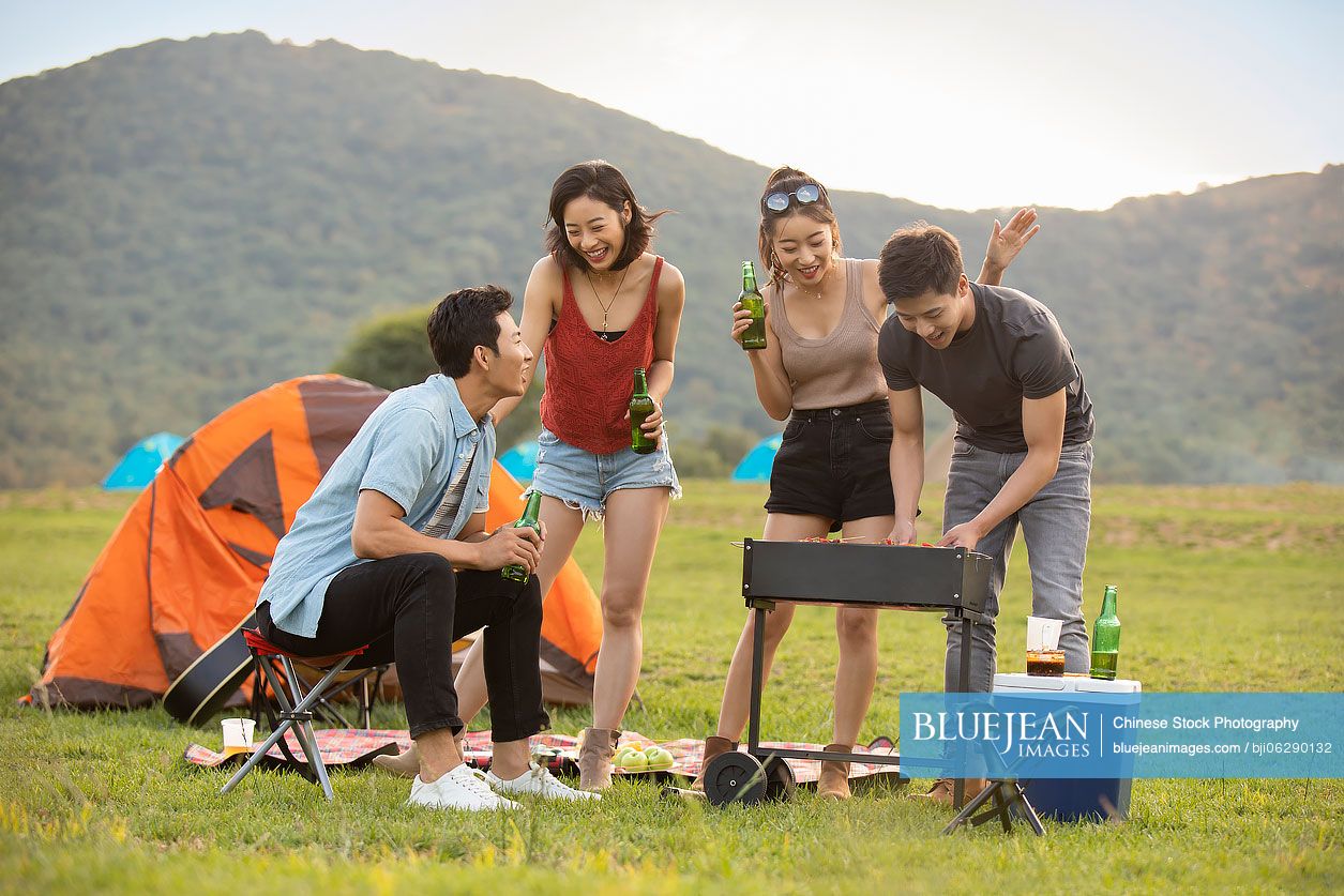 Happy young Chinese friends barbecuing outdoors