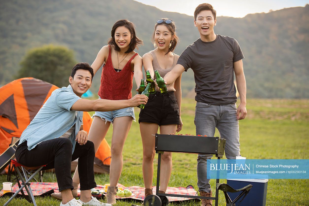 Happy young Chinese friends barbecuing outdoors