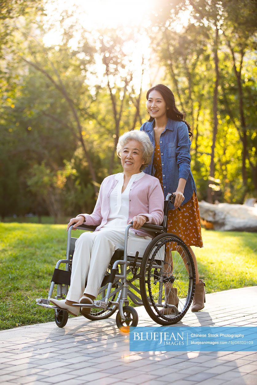 Happy Chinese mother and daughter relaxing in park