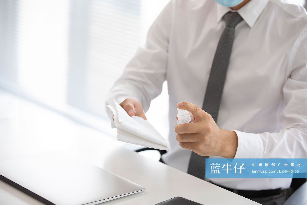 年轻的商务男士在办公室使用消毒液杀菌消毒