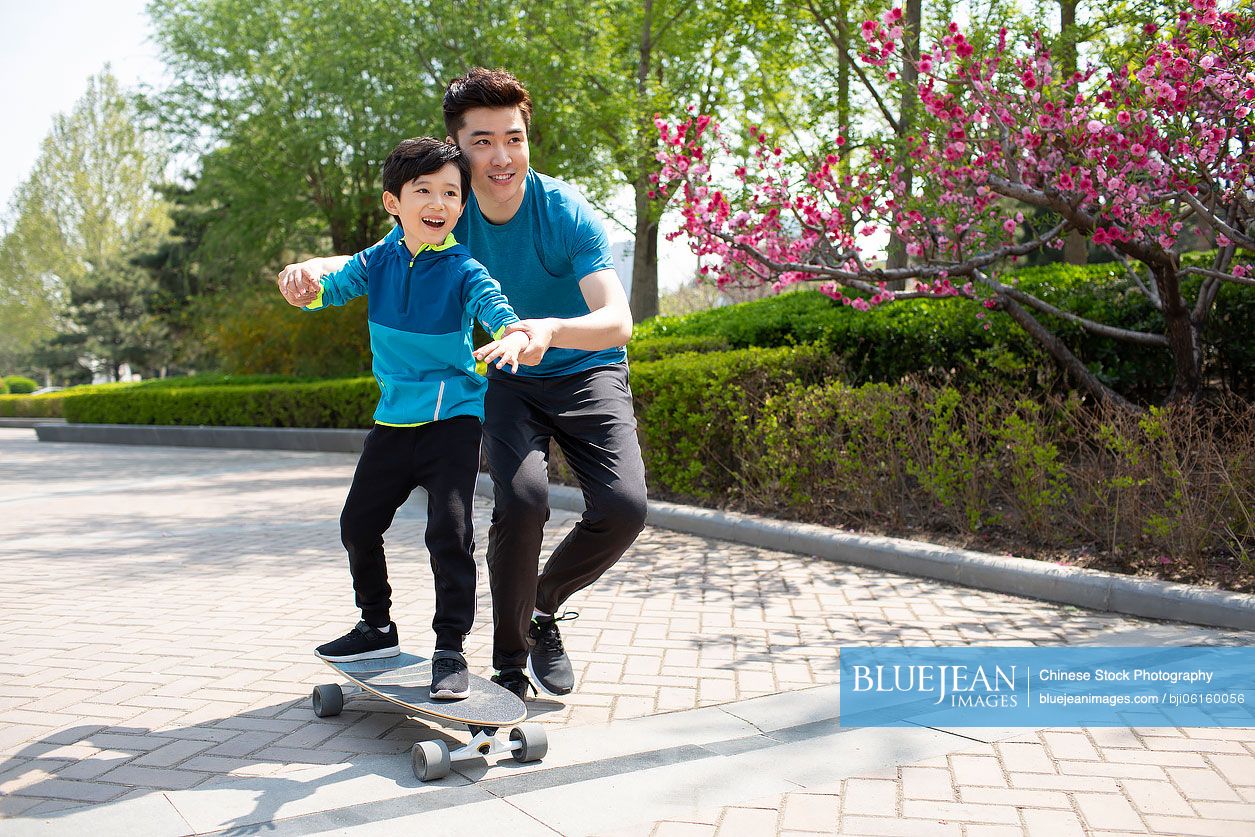 Chinese father teaching his son to skateboard