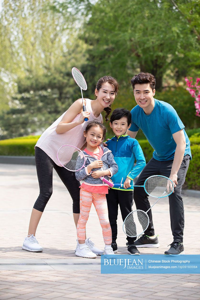 Happy young Chinese family playing badminton in park