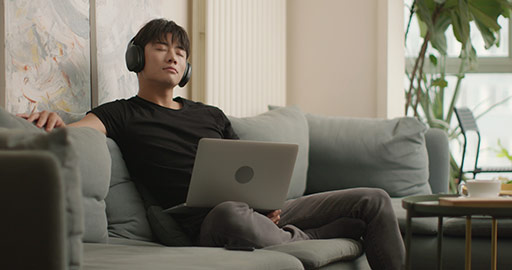 Young Chinese man listening to music with headphones at home,4K