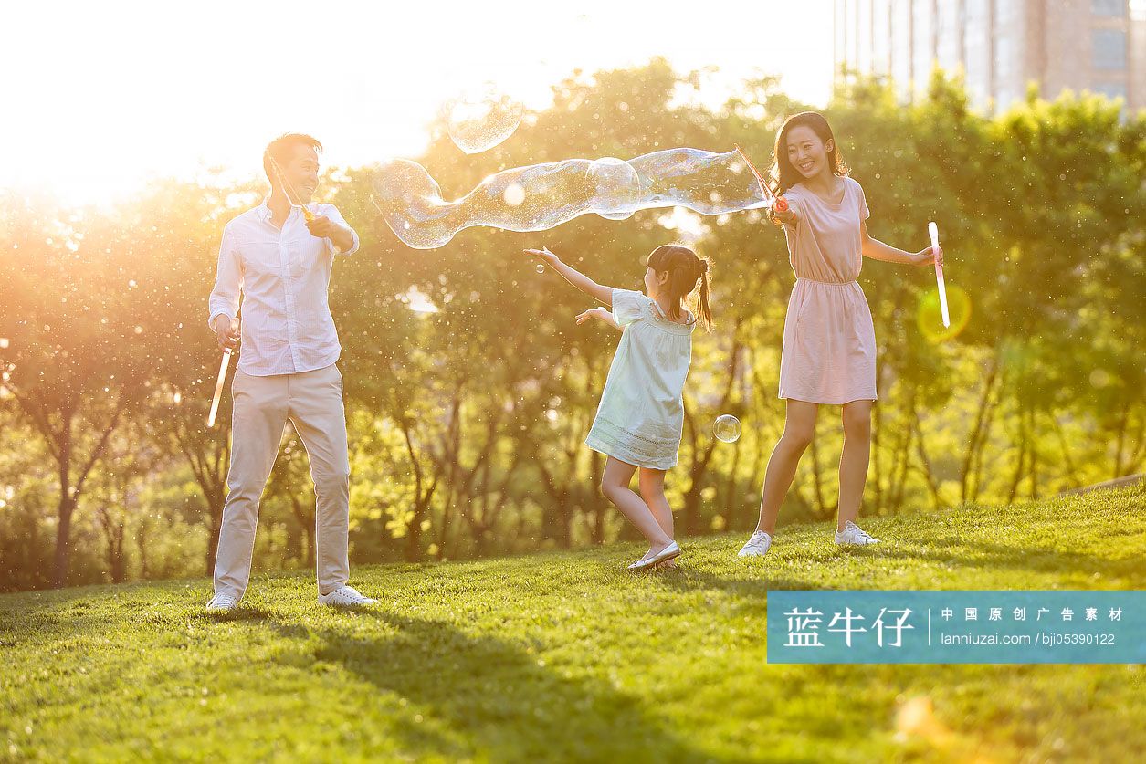 快乐的年轻家庭在公园玩泡泡