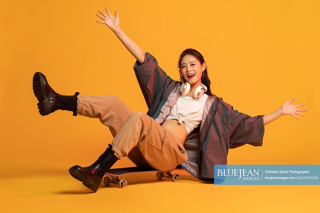 Fashionable young Chinese woman skateboarding