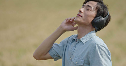 Happy young Chinese man wearing headphones in wheat field,4K