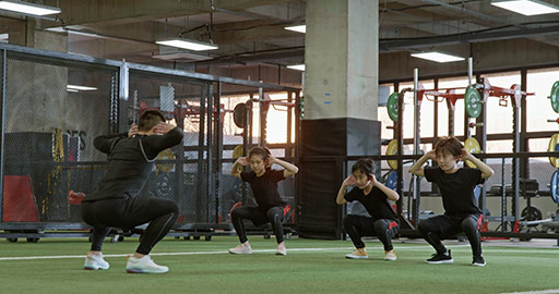 Active Chinese children having exercise class with their coach in gym,4K