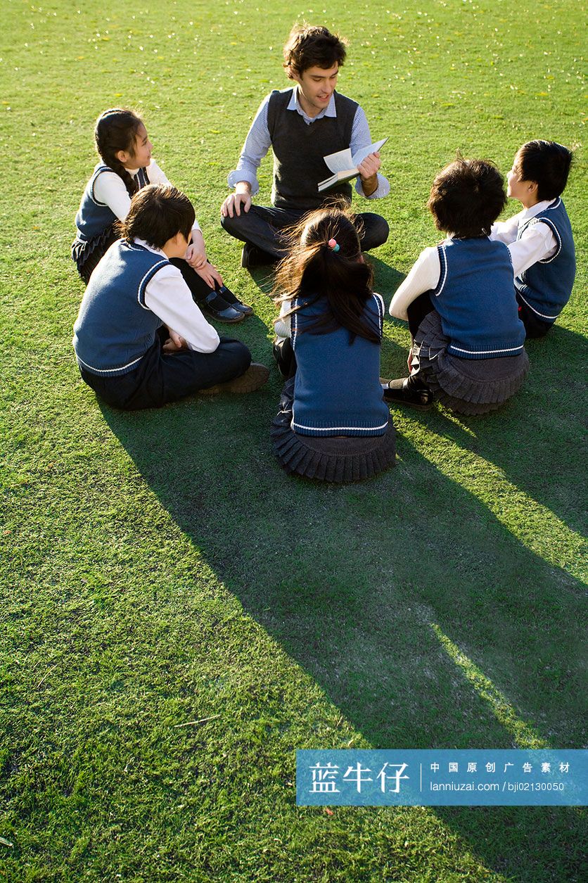 小学生在草地上围着老师学习